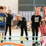 A group of children all of varying heights and gender are stood mid action. It looks as if they are playing musical statues.