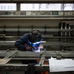 Metalwork apprentice welding in workshop