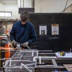 Scenic metalwork fabricator apprentice using grinding equipment, sparks are flying.