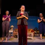 The writer of 'Barrier(s)', New Views winner 21/22, Eloise Pennycott standing on stage receiving applause alongside the two female actors