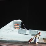 A model box featuring an elderly woman walking across a white landscape with an oven in the background