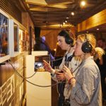 Two people listening to a film on headphones at the Linbury Prize exhibition 2023