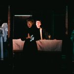 A woman prays - behind her are two praying angels with wings and a priest in front of an altar.