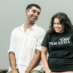 A man wearing a white shirt and a woman wearing a black shirt are laughing.