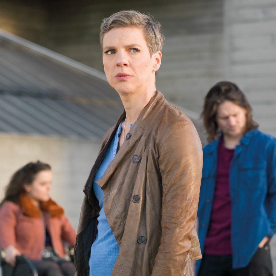 All of Us - photo of Francesca Martinez in an urban setting, with two cast members, out of focus, behind her