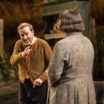 Siobhán McSweeney as Maggie wearing a long grey floral cardigan standing next to Ardal O'Hanlon as Jack in a brown cardigan.