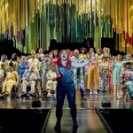 Beth Hinton-Lever singing at the front of the stage, backed by a large ensemble cast