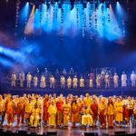 A large group of people stand on stage smiling.