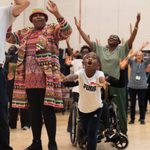 A group of people dance with their arms in the air.