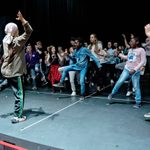 A group of people rehearsing a group dance number on stage.