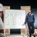 A man in an Englan coach jacket points at a whiteboard on which is written Story I II III. Men in white england kits stand and sit looking at the board. Another, older man in an England tracksuit, stands to one side