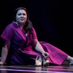 Ebony Jonelle as Rosalind, dressed in a purple dress, sitting on the floor and shoeless