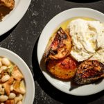 On a table, a selection of small plates of Italian dishes are spread out.