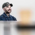 Jamie Lloyd sitting in the rehearsal room wearing a baseball cap and a denim shirt.