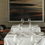 LASDUN Restaurant - a light interior, with two tables, each set for two., with a large framed picture on the wall behind