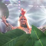 A performer on the River Stage, surrounded by large green leaves and bright stage lights.