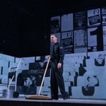 A cleaner sweeps the floor of the Othello stage set with a long-handled wooden broom