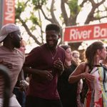 A group of people in summer attire dancing as part of a crowd. They are smiling and laughing.