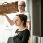 Rosie Sheehy in a dark round-neck top in the foreground, with Paul Brennen behind her, wearing a white t-shirt and carrying a large wicker basket.