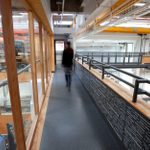 A shot of the Sherling High Level walkway, with a blurred figure walking away, backstage at the National Theatre, a balcony overlooking the set and prop-making departments