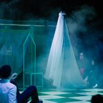 Hamlet is on the floor facing the ghost of his father. The ghost is dressed in a long white sheet with a crown on it's head.