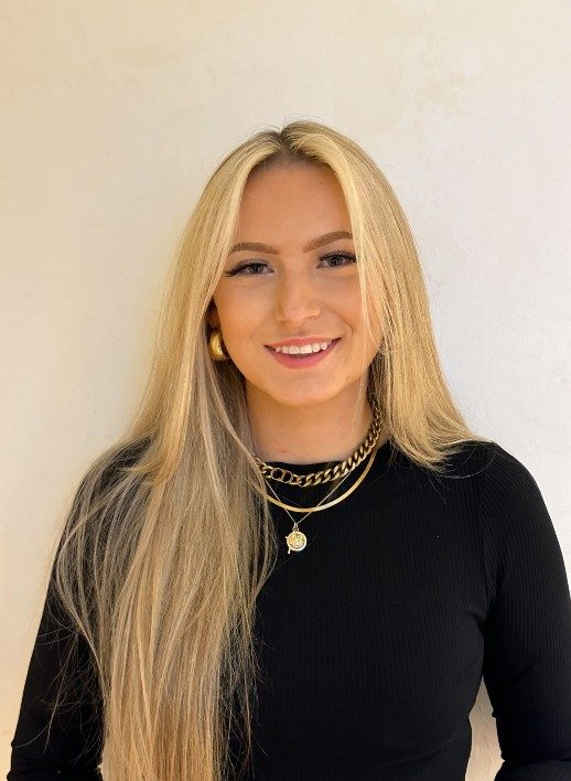 A person with very long blonde hair wearing a long-sleeved black top