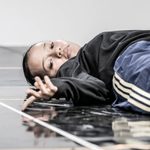 Taylor Russell lying on the floor of the rehearsal room wearing a black top.