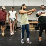 Four of the cast of A Strange Loop standing and interacting in pairs, in rehearsals.