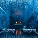 A priest stands at an altar with two candles, facing a congregation sitting on rows of chairs. Rain is falling, mist billows and the whole image is suffused in blue.