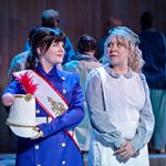 Actor Beth Hinton-Lever dressed as a palace guard looking at fellow actor, Daisy Ann Fletcher, dressed in a hat and apron.