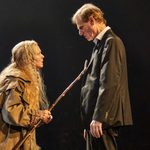 Finty Williams (Old Mrs Hempstock) holding a long stick, placed on the chest of Trevor Fox (Dad), whoc looks down into her face