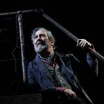 A production image of 'Translations' at the National Theatre, 2018, featuring actor Ciaran Hinds standing underneath a rusty railing