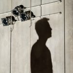 Andrew Scott's shadow against a wall, beneath a rig of small spotlights.